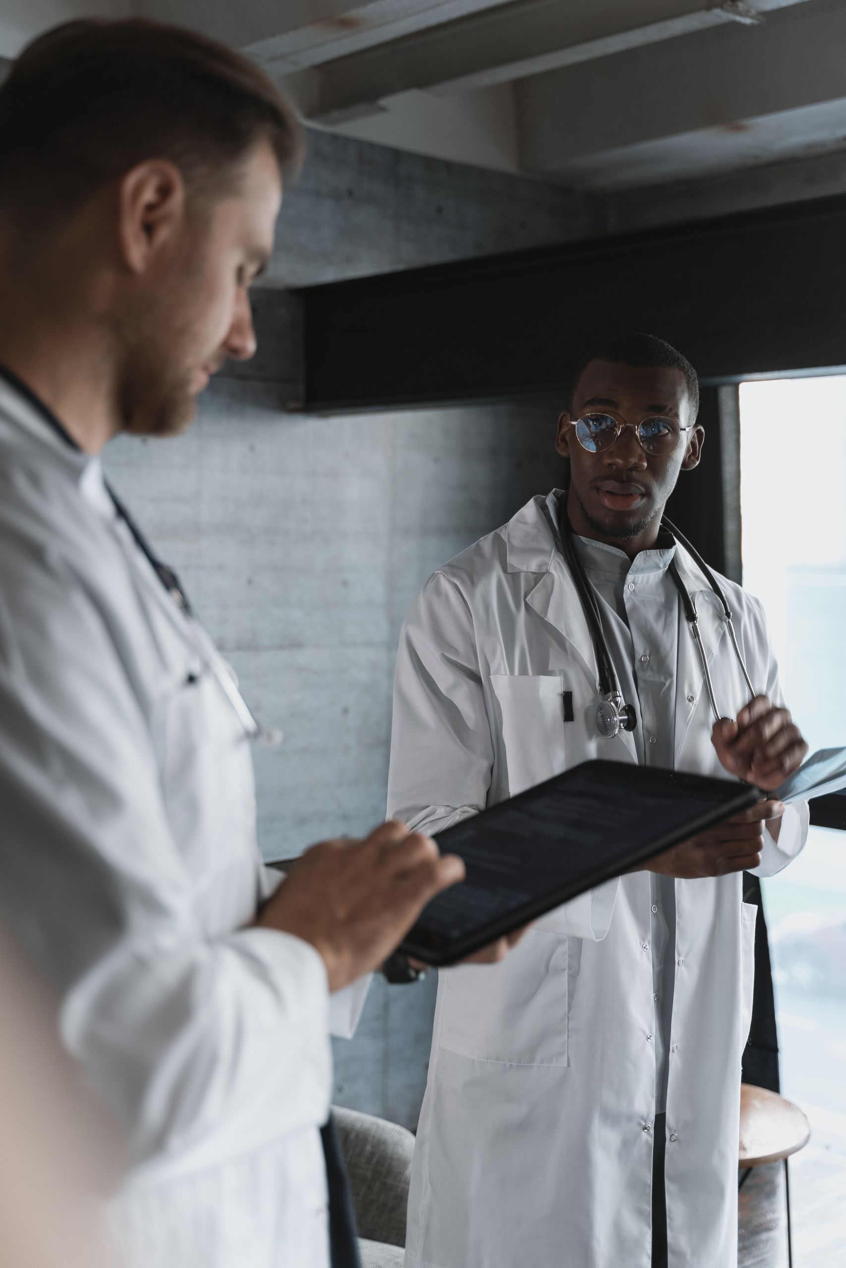 Two doctors reviewing patient information on a tablet in a modern office setting.